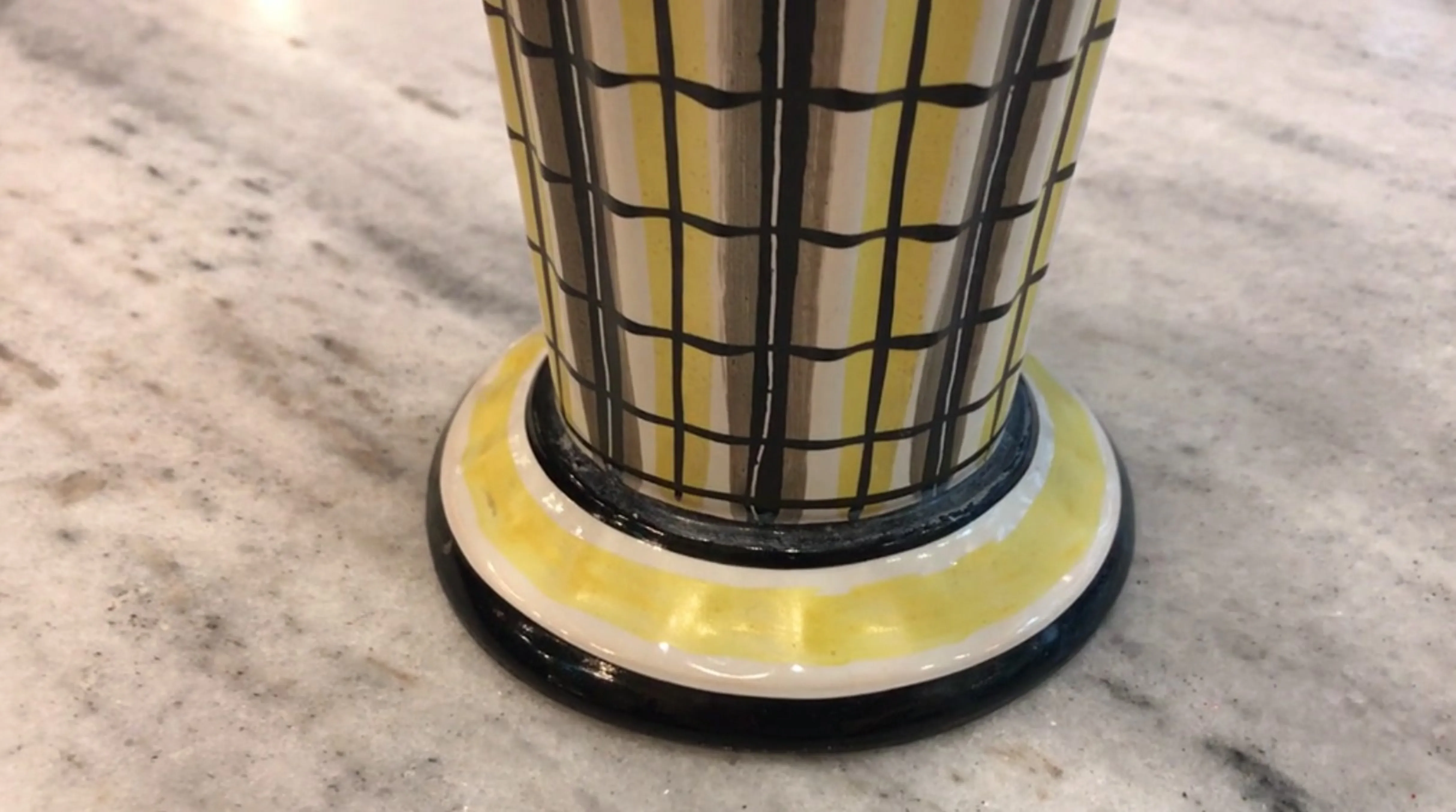 Copo de cerâmica antiga com padrão xadrez amarelo em fundo claro.