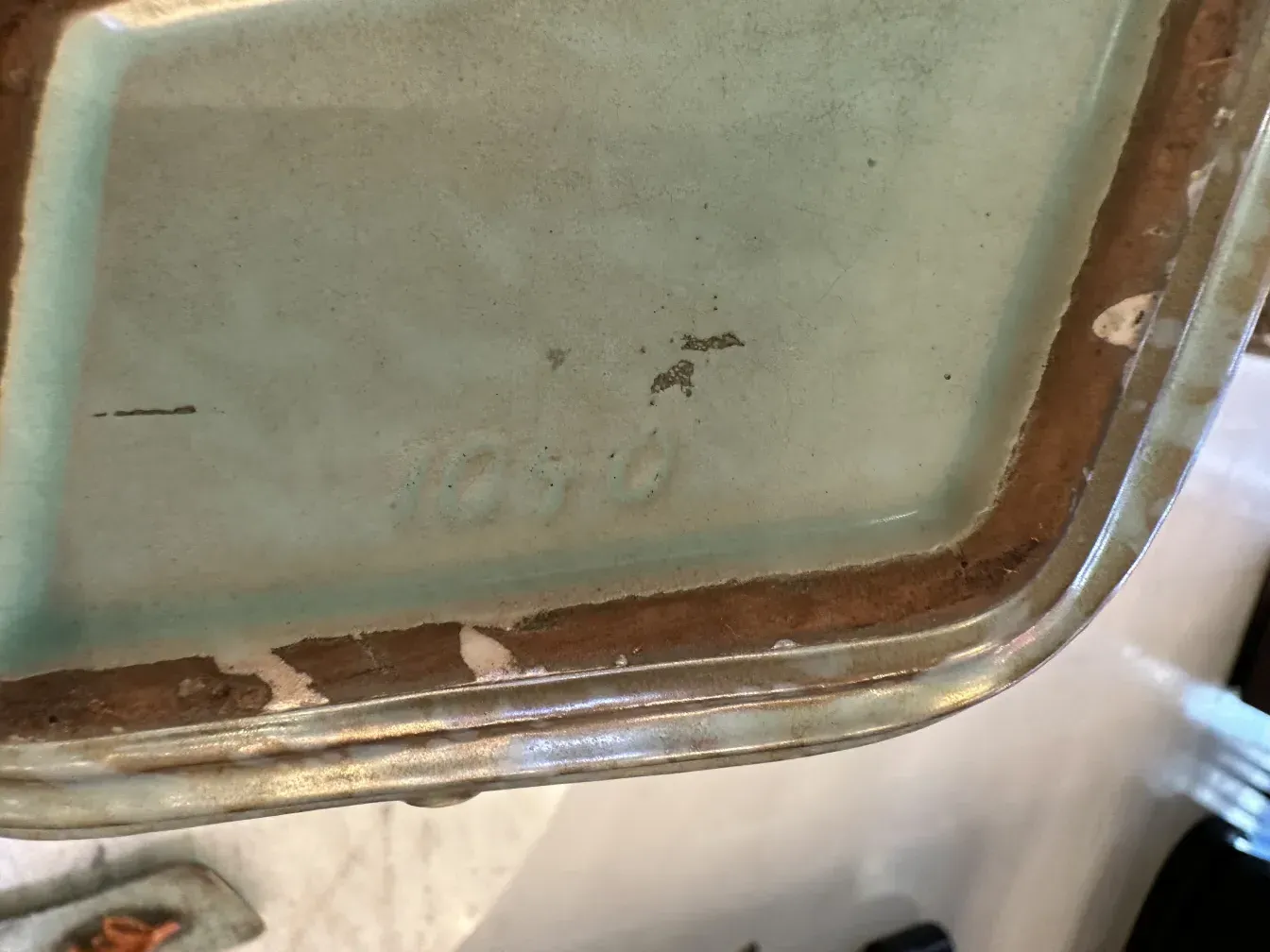 Ceramica antigua decorada con hojas en tonos naranja y marrón