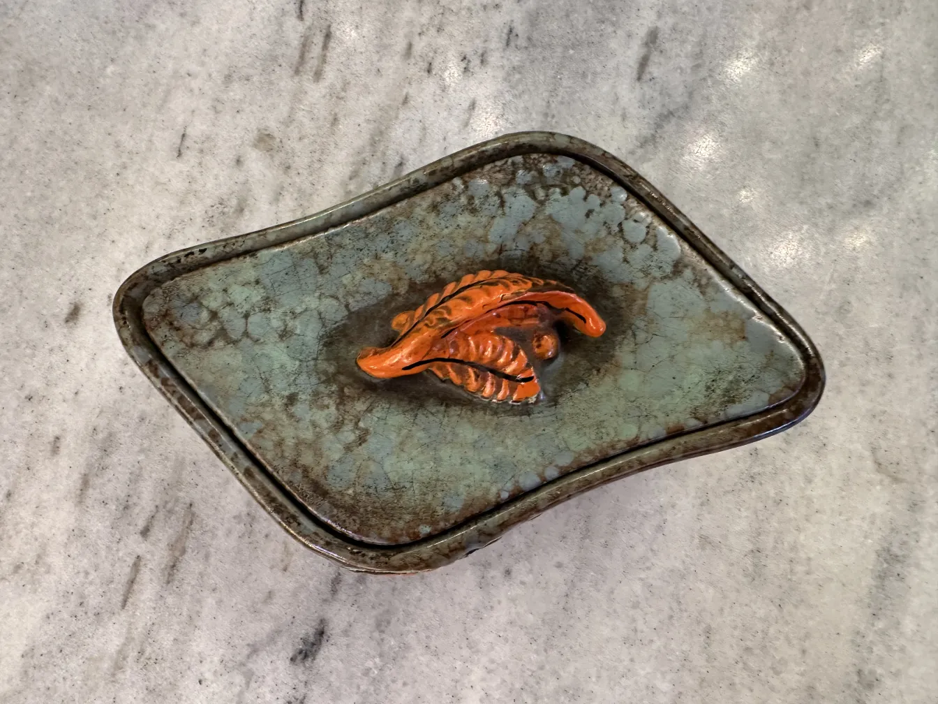 Ceramica antigua decorada con hojas en tonos naranja y marrón