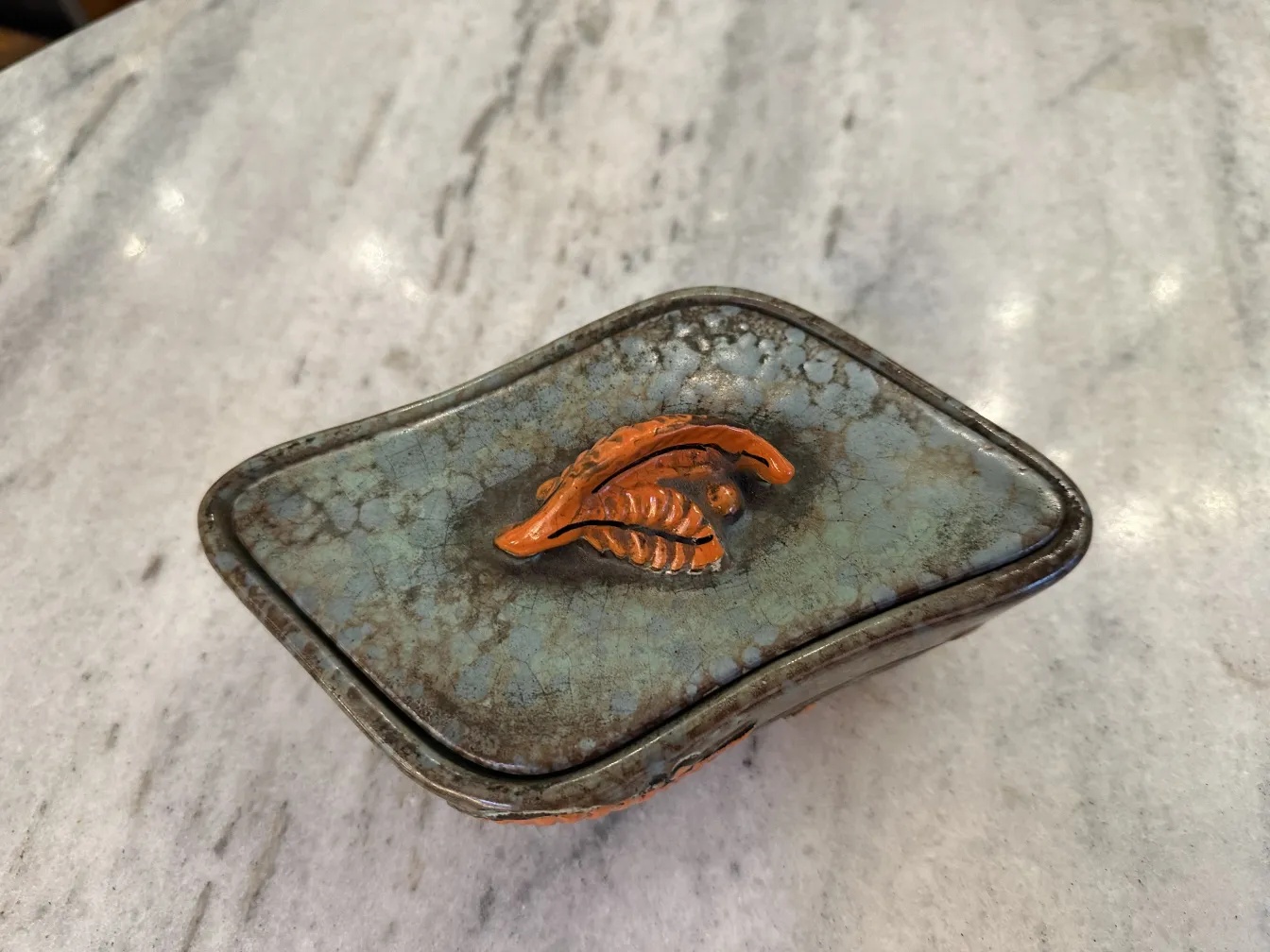 Antica ceramica decorata con foglie in tonalità di arancione e marrone