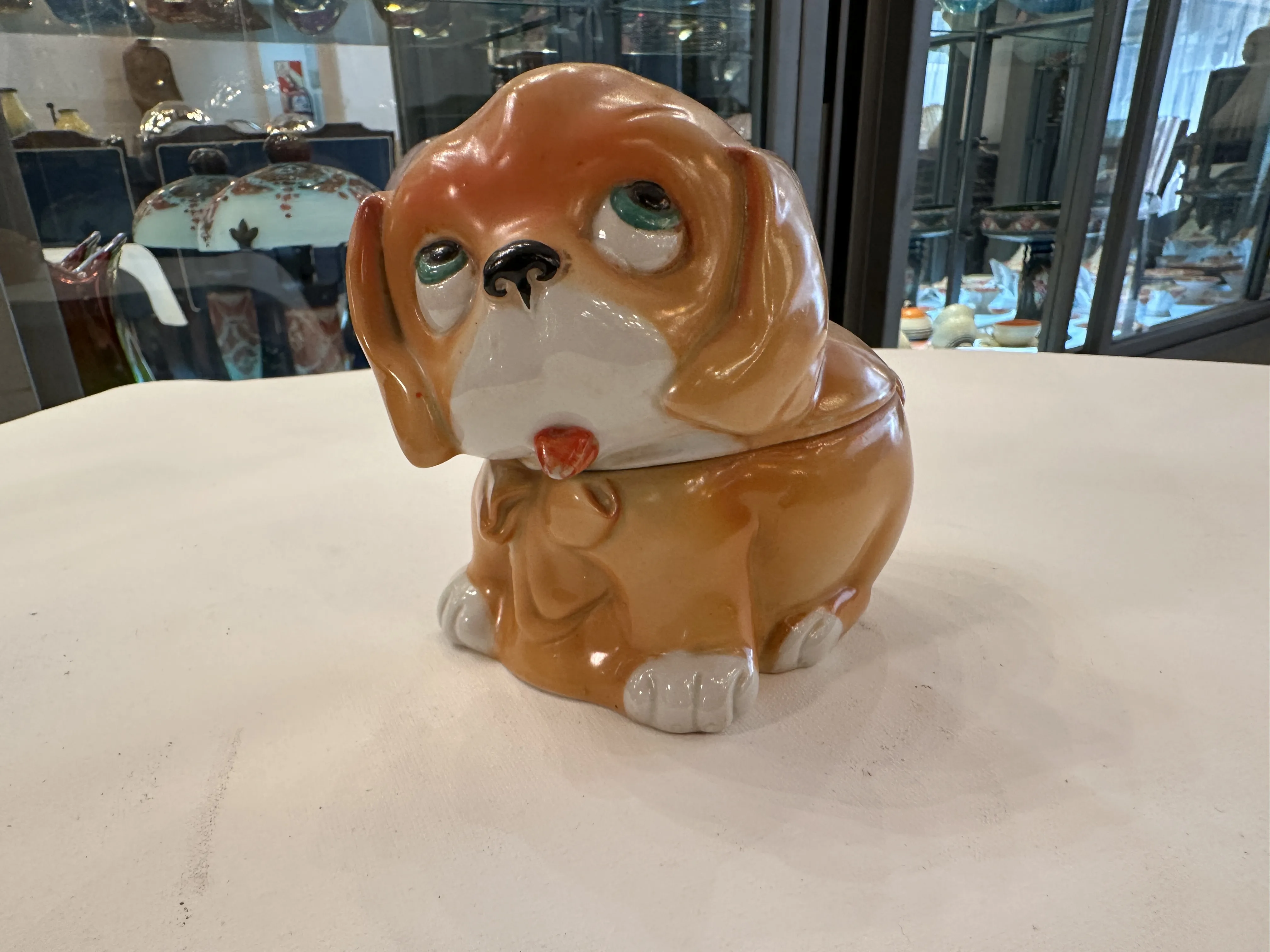 Antiga cerâmica em forma de cachorro com uma expressão adorável, em tons alaranjados e detalhes claros.