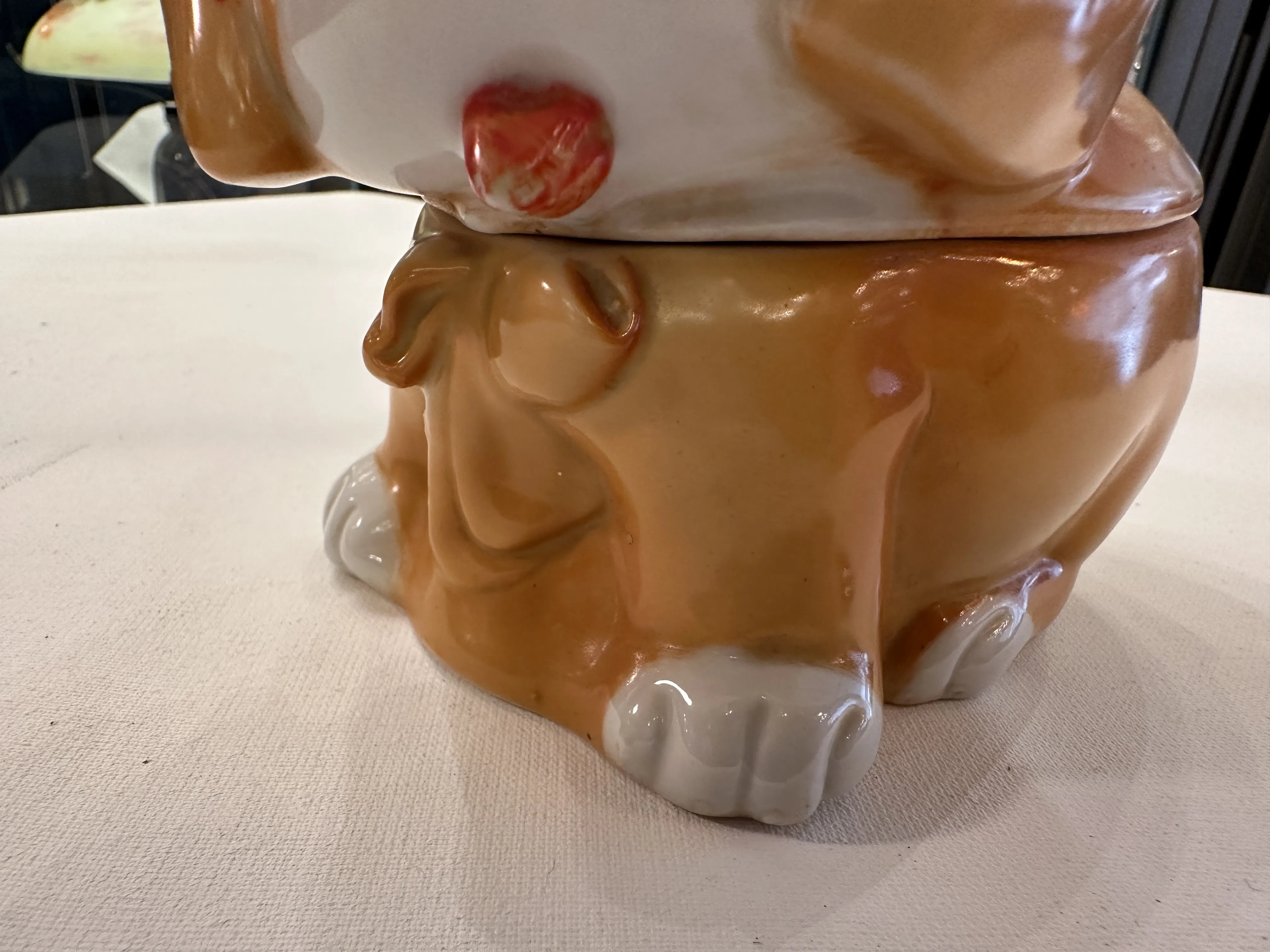 Antica ceramica a forma di cane con colori caldi e zampe adorabili.