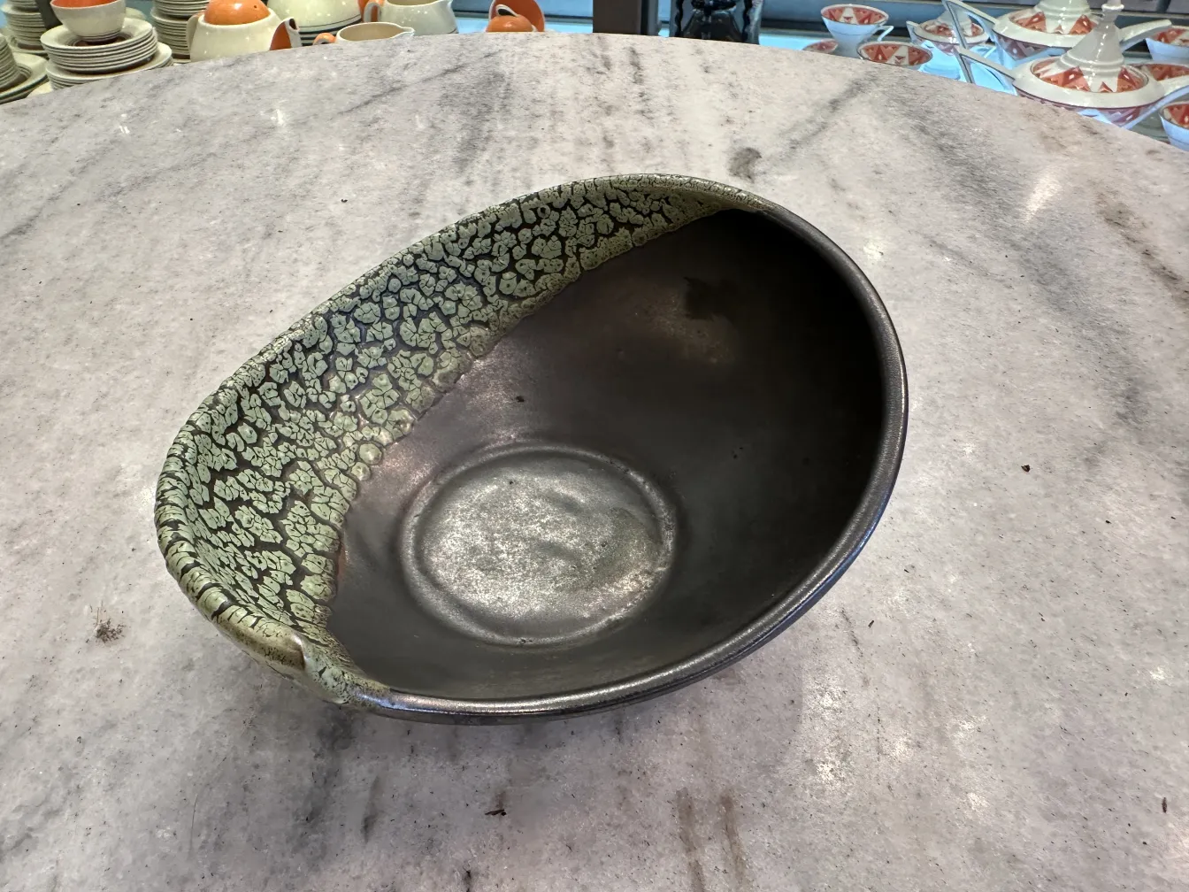 Antique decorated ceramic bowl with green textured details resembling leaves. Displays an elegant and appealing design.