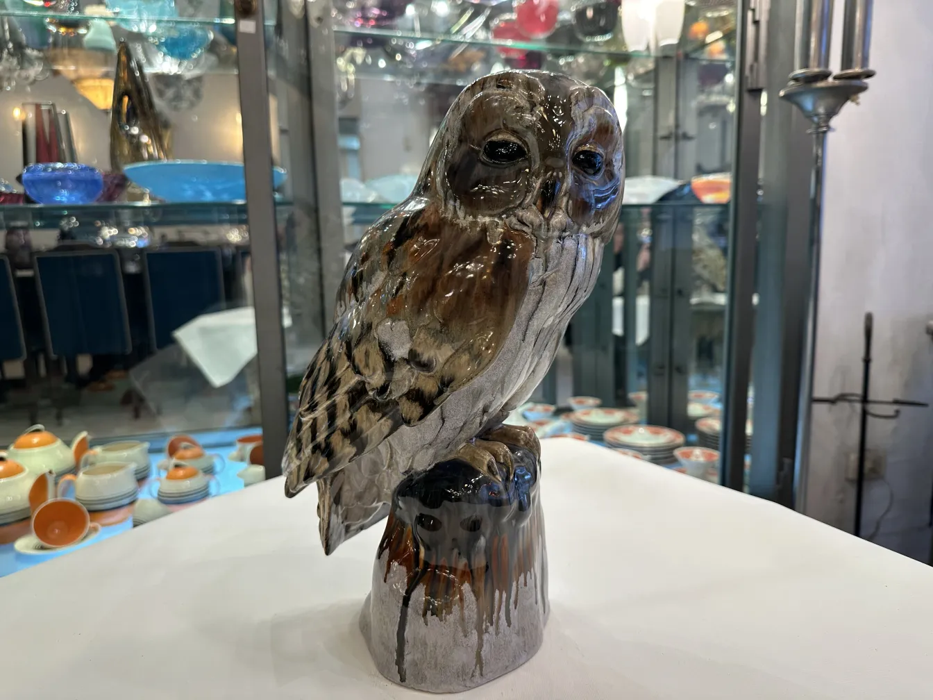 Antique ceramic figure of an owl, realistic color, displayed in an antique environment.