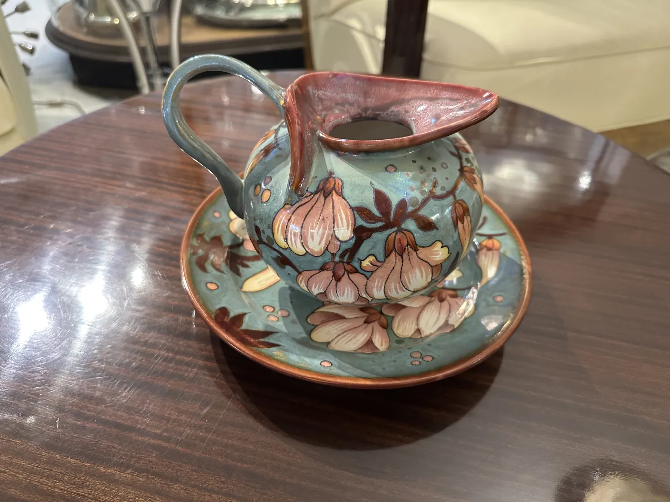Antigua cerámica con flores y base decorativa, sobre una mesa oscura
