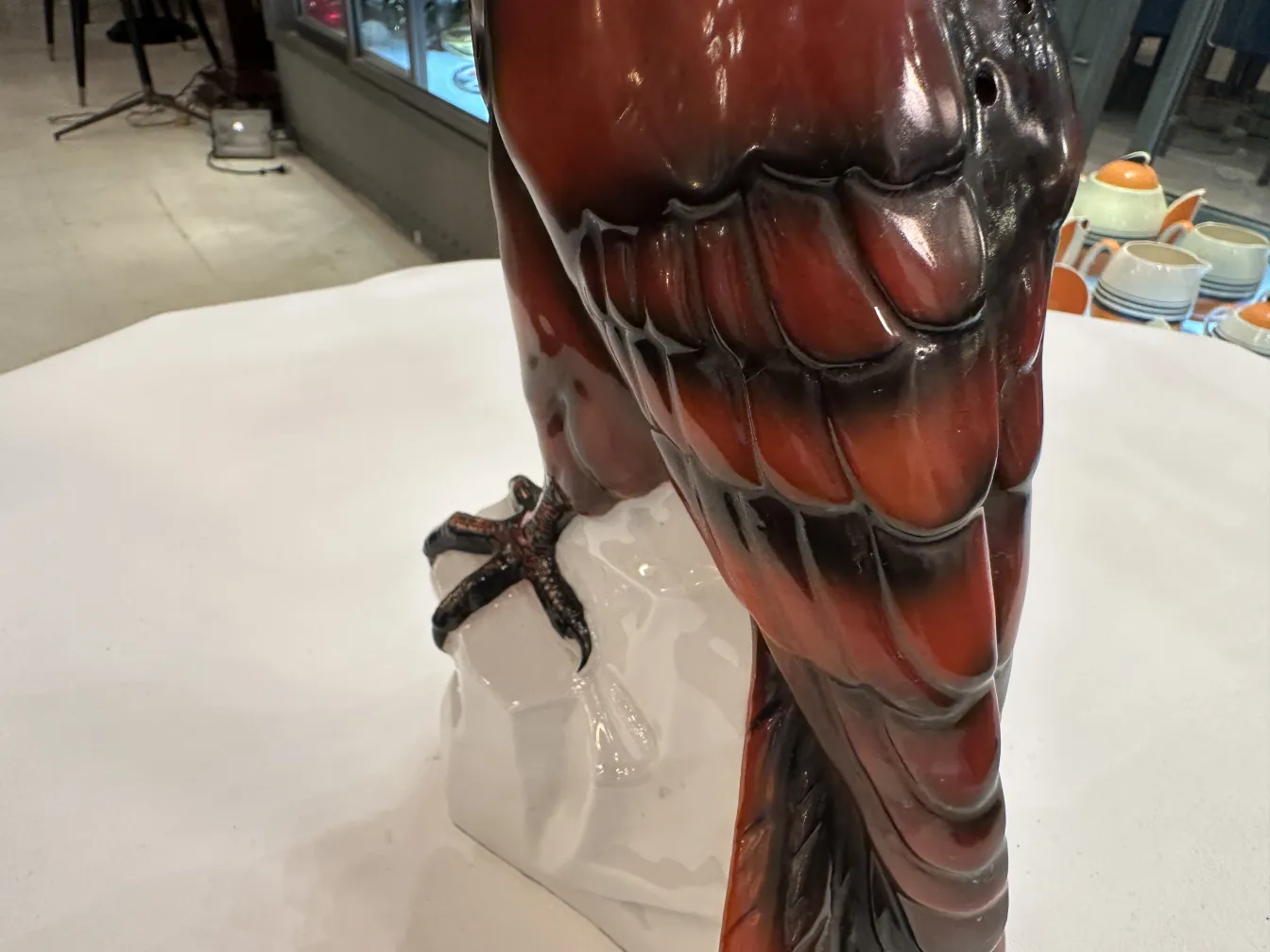 escultura cerâmica com detalhes intrincados em tons escuros e claros, ambientada em um mercado de antiguidades
