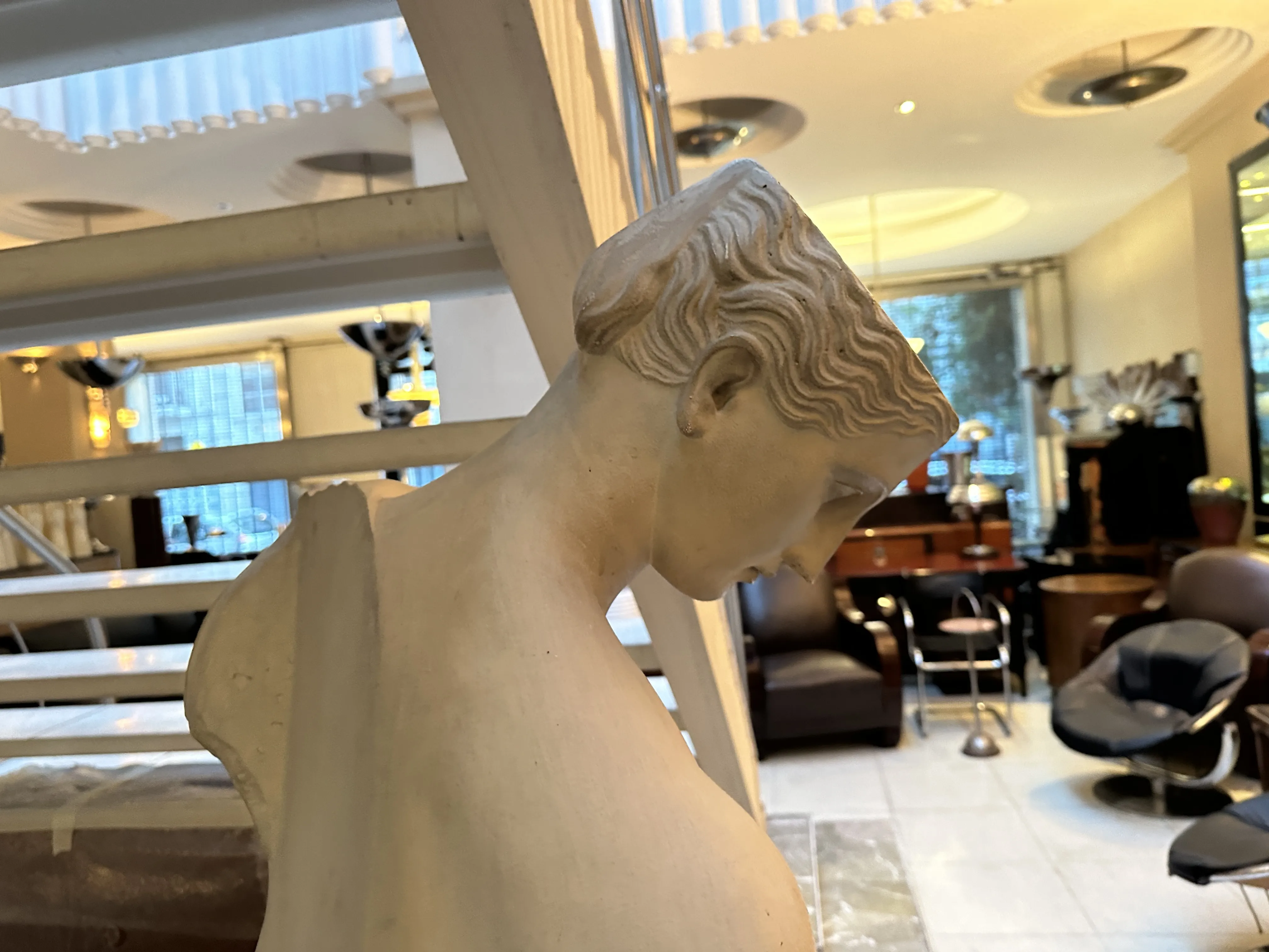 escultura antiga de figura feminina contemplativa em interior