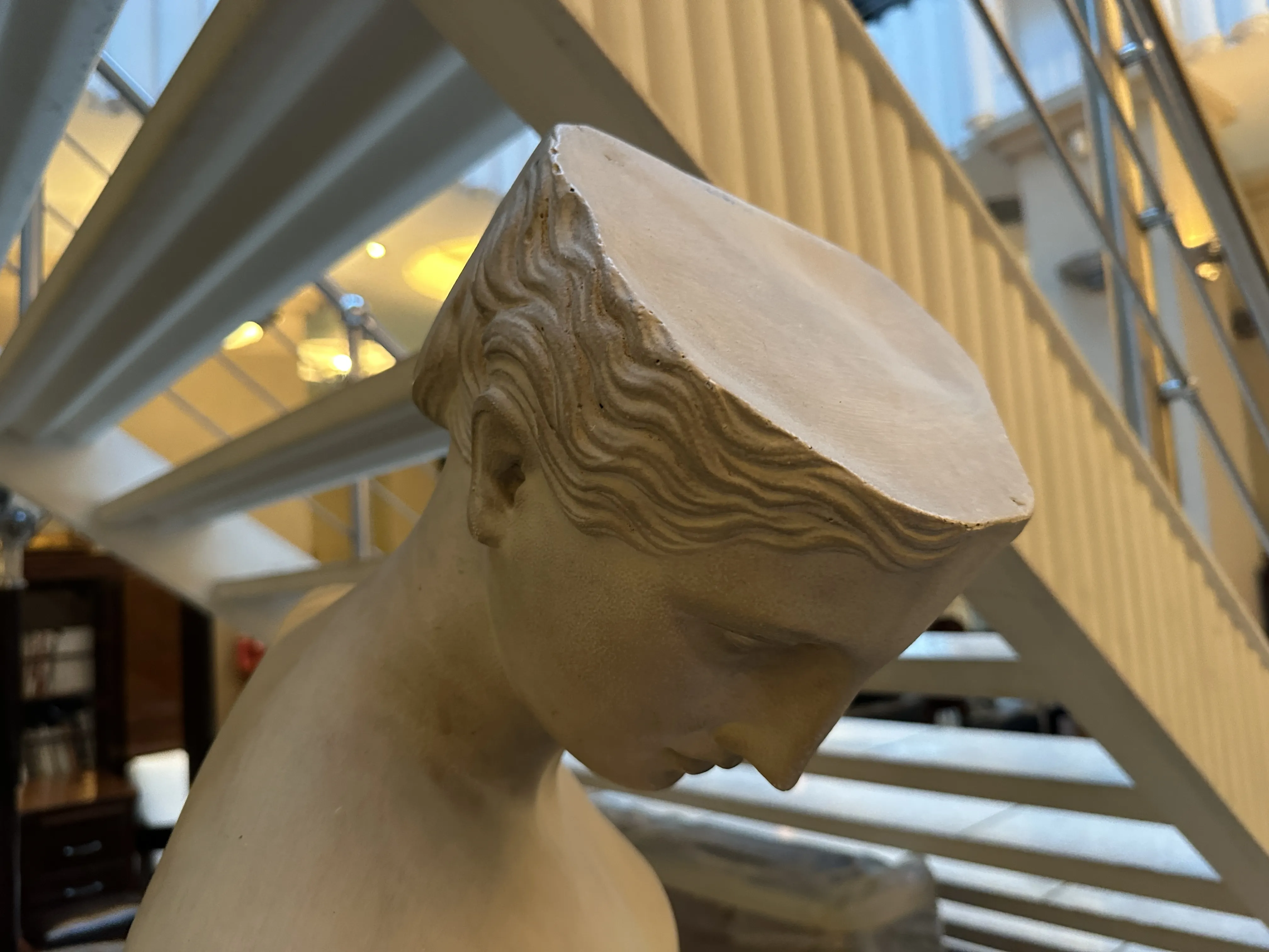 antique sculpture with facial features, staircase background