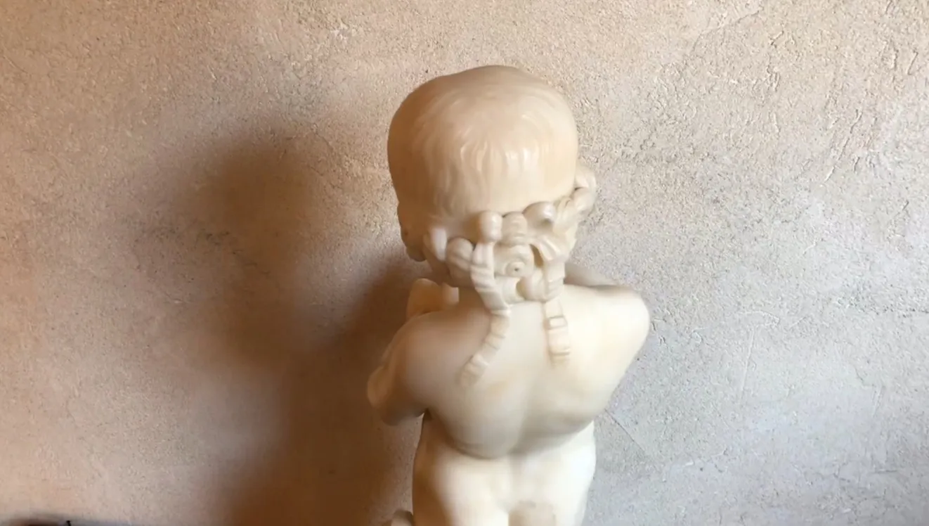antique sculpture of a child holding a bird