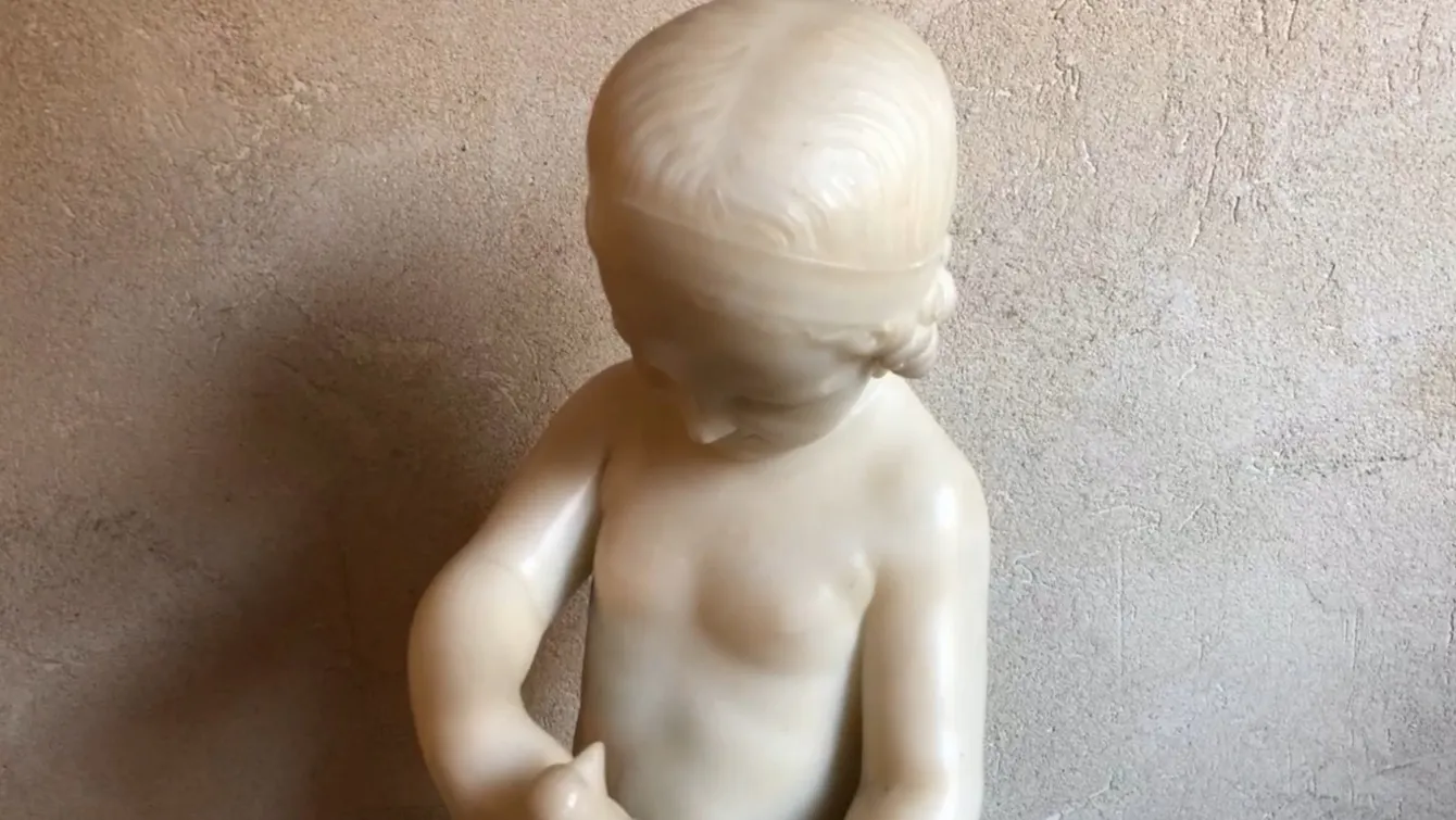 escultura antigua de un niño sosteniendo un pájaro