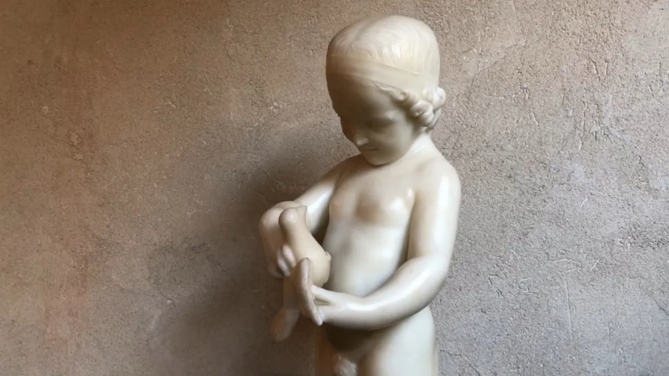 antique sculpture of a child holding a bird