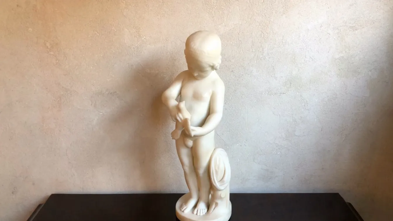 escultura antigua de un niño sosteniendo un pájaro
