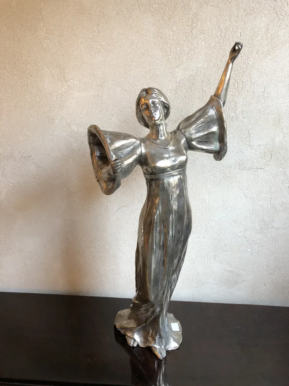 escultura antiga de figura feminina com os braços erguidos