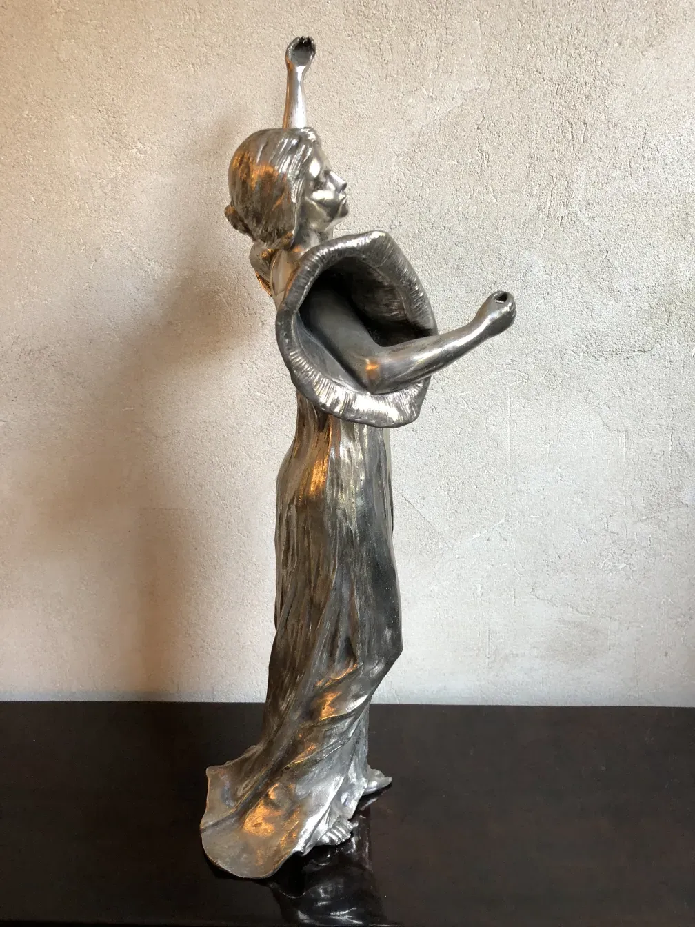 scultura antica figura femminile elevata con braccia alzate, dettagli sottili