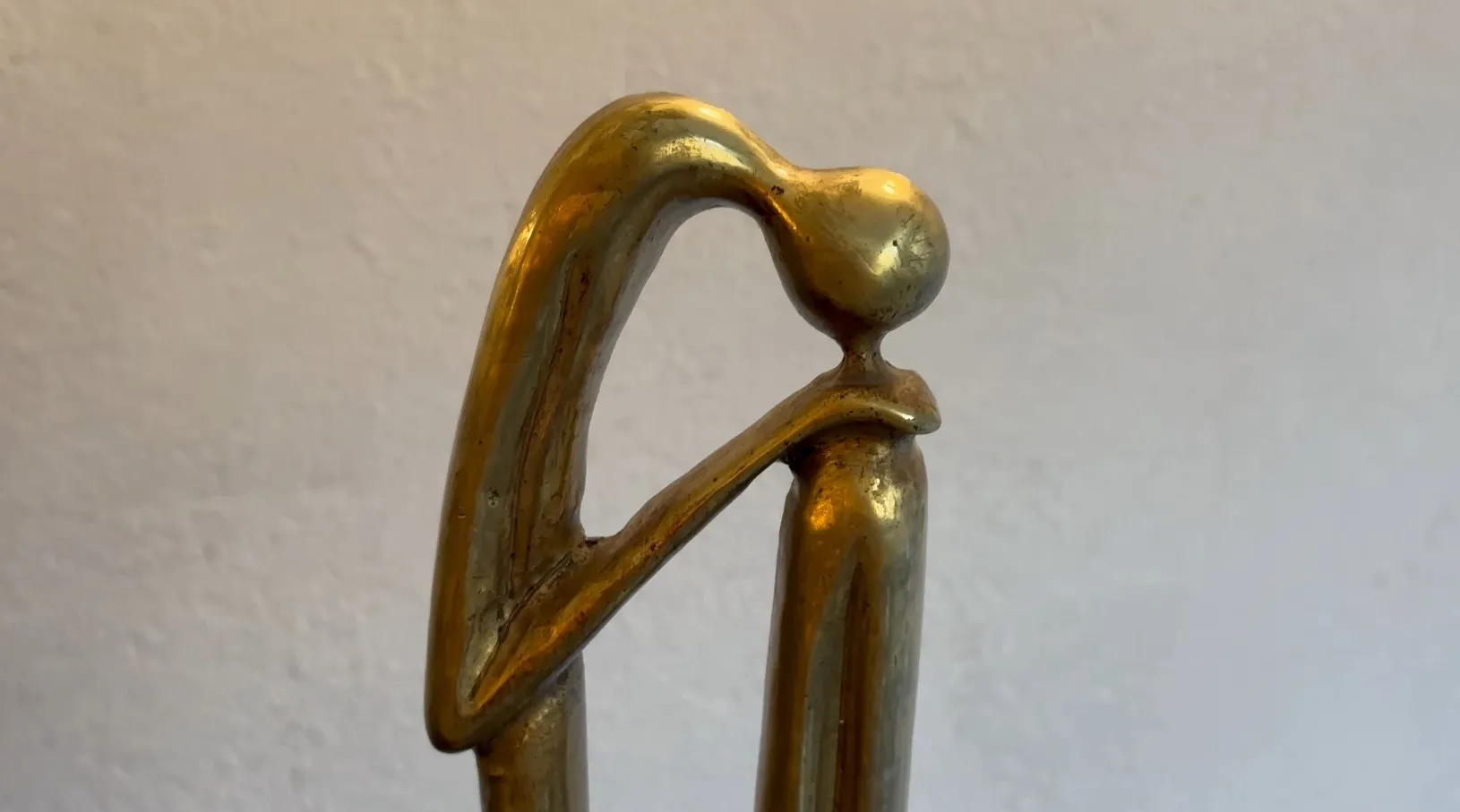 Escultura antigua con forma estilizada y base decorativa.
