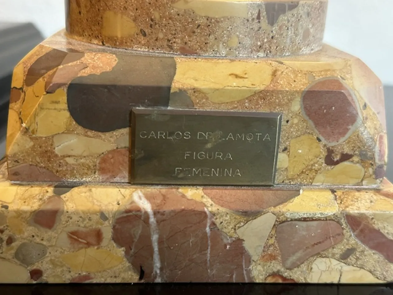 Escultura antiga com forma elegante e base decorativa.