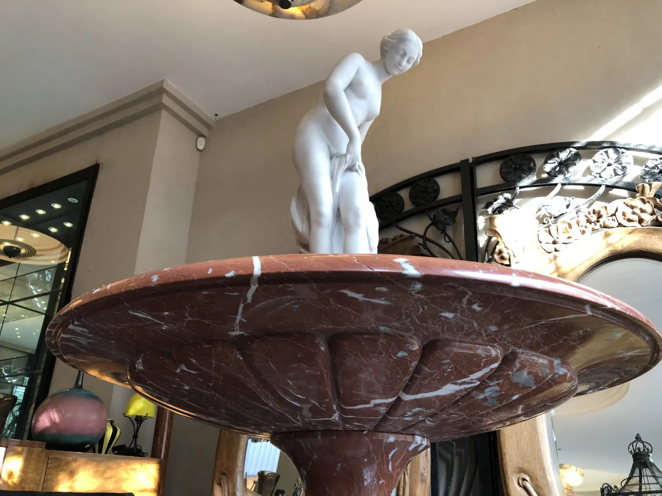 fonte antiga em estilo art nouveau com figura esculpida, ambiente elegante