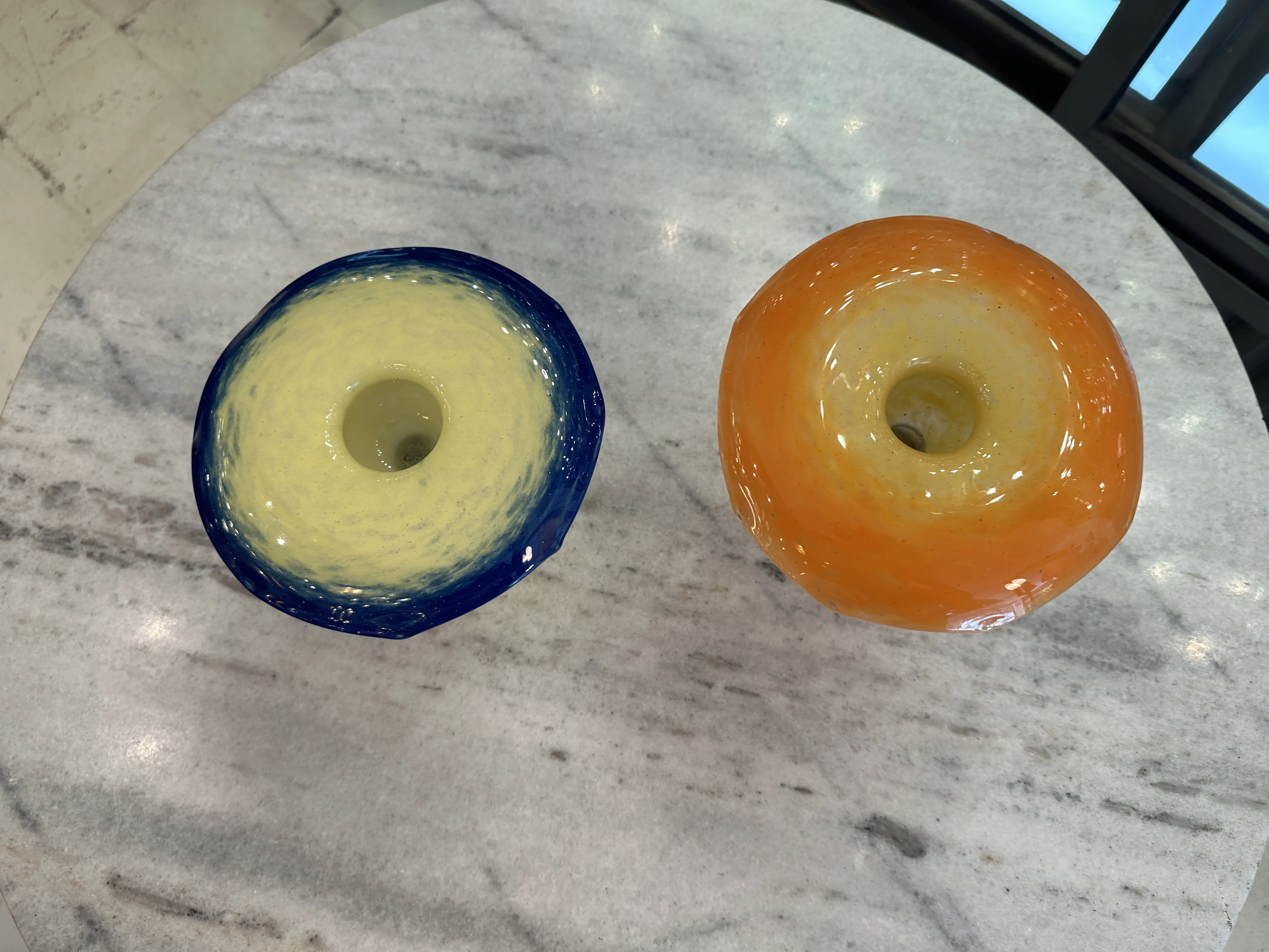 Two antique signed glass vases by Schneider, one blue and the other orange on a table.