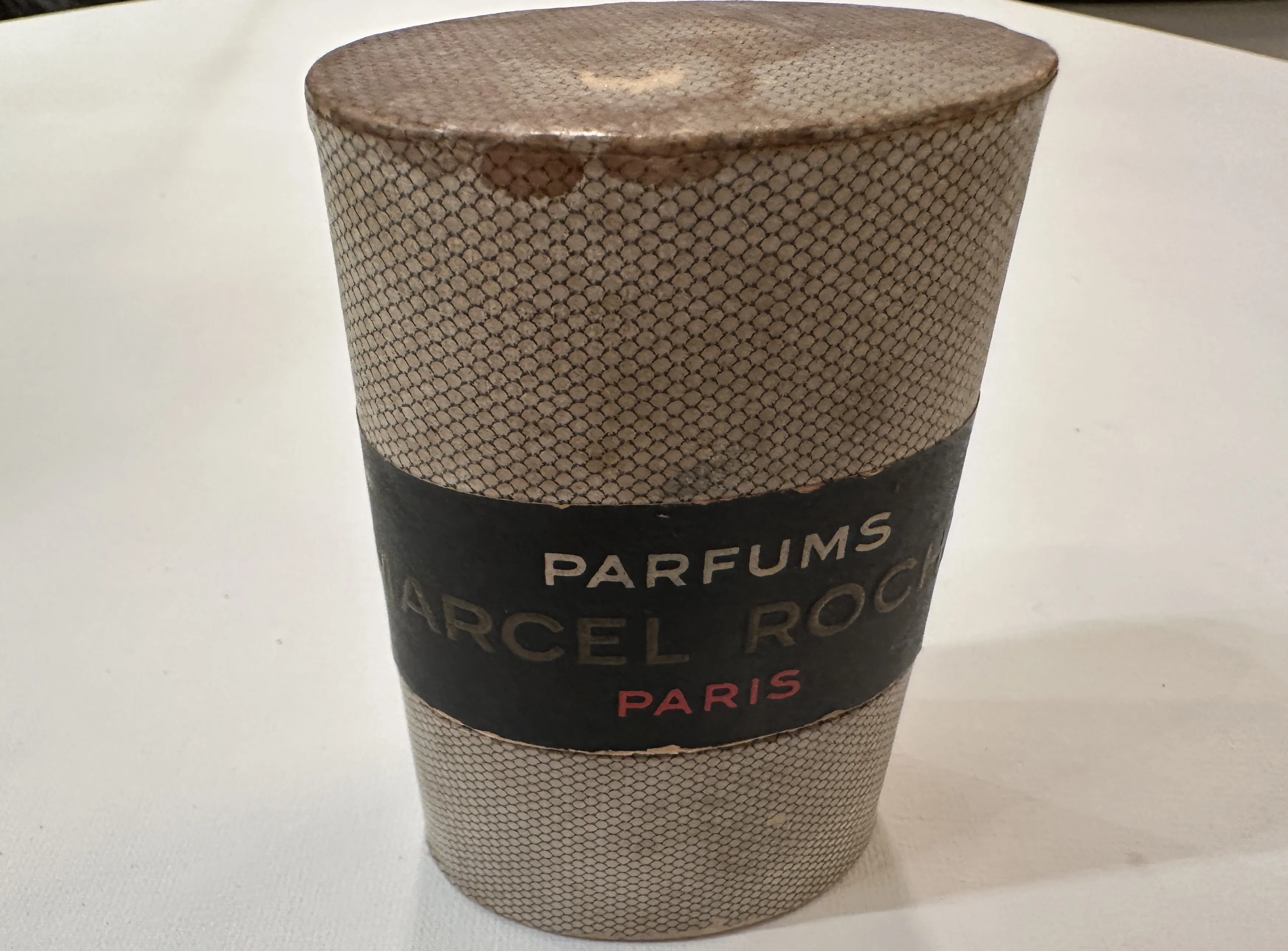 Flacon de parfum ancien avec détails sur le couvercle et l'étiquette.