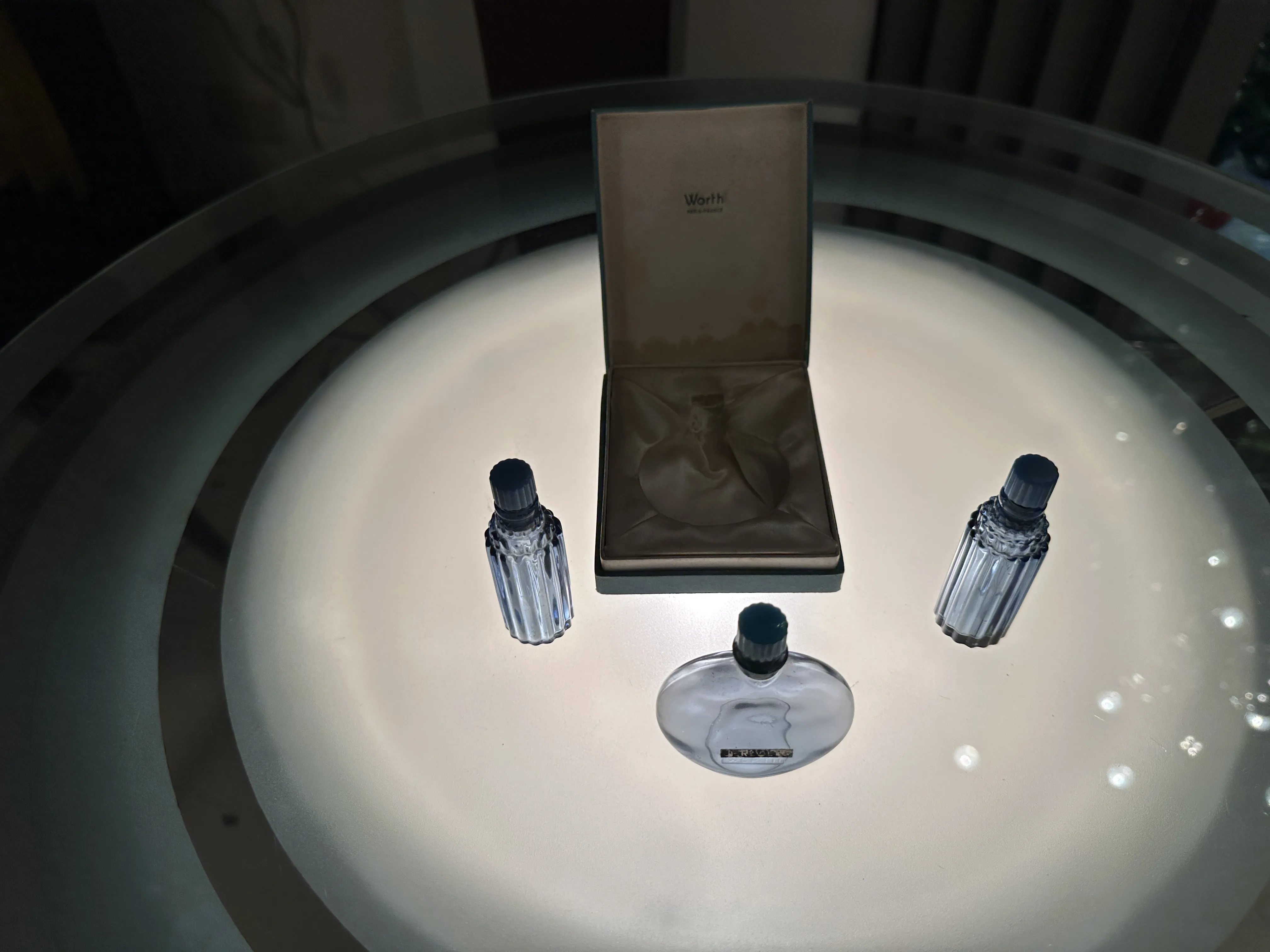 Três frascos de perfume antigos sobre uma mesa iluminada