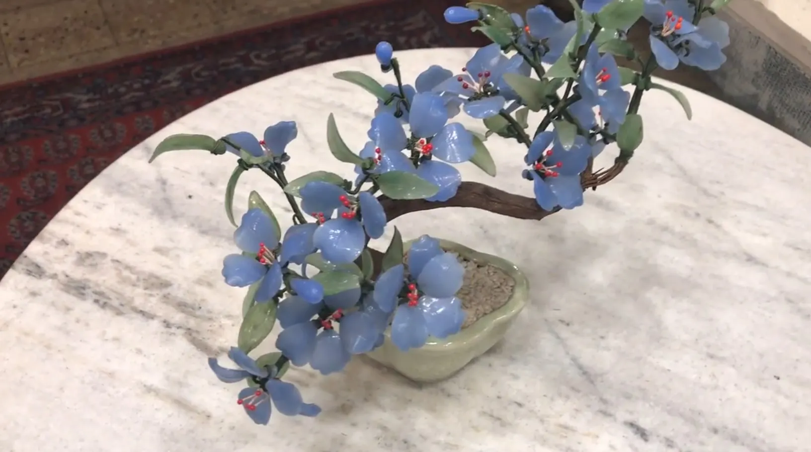 Bonsai antico con fiori blu su un tavolo in marmo