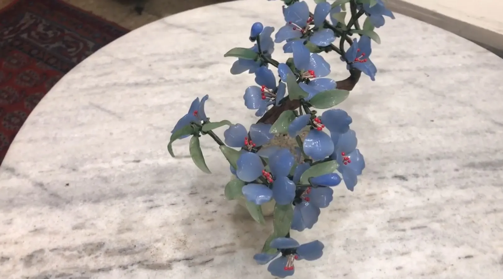 Bonsai ancien avec des fleurs bleues sur une table en marbre.