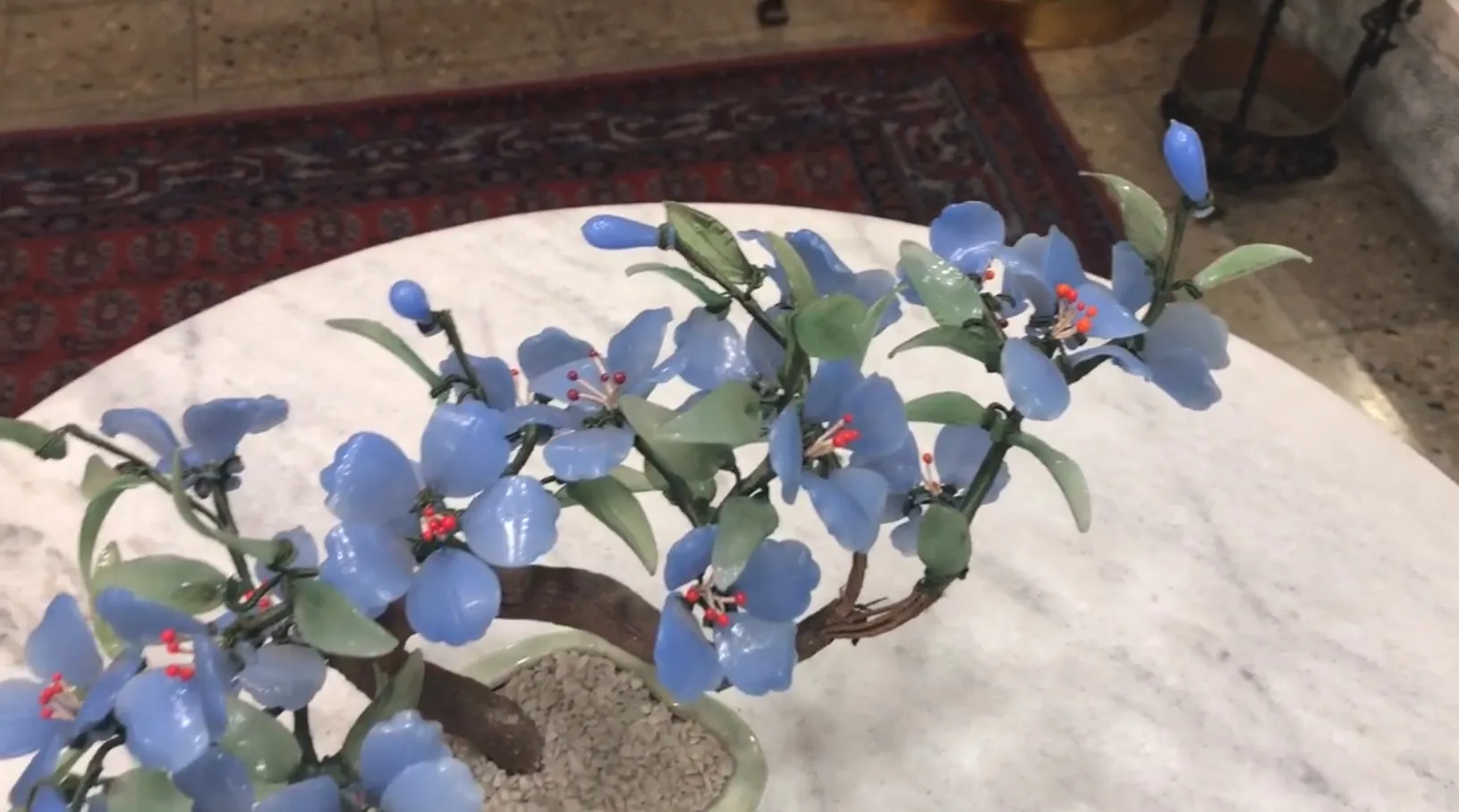 Bonsai antico con fiori blu e foglie verdi.