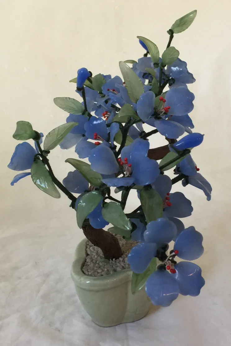 Antiker Bonsai mit blauen Blumen und grünen Blättern in einem Topf