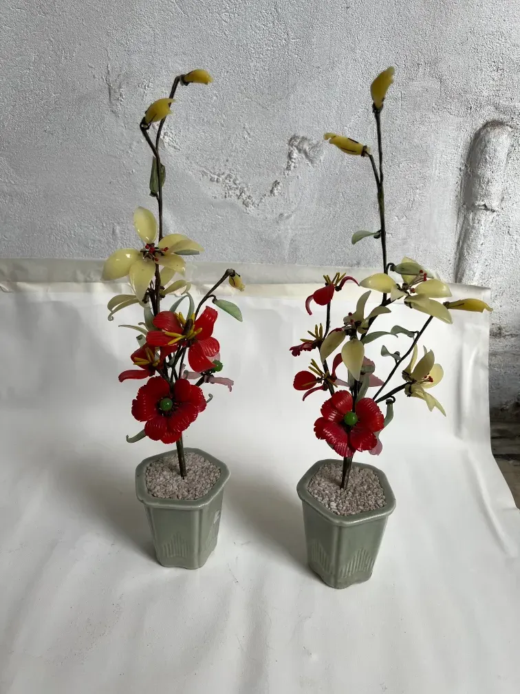 Bonsái antiguo con flores rojas y amarillas en macetas.