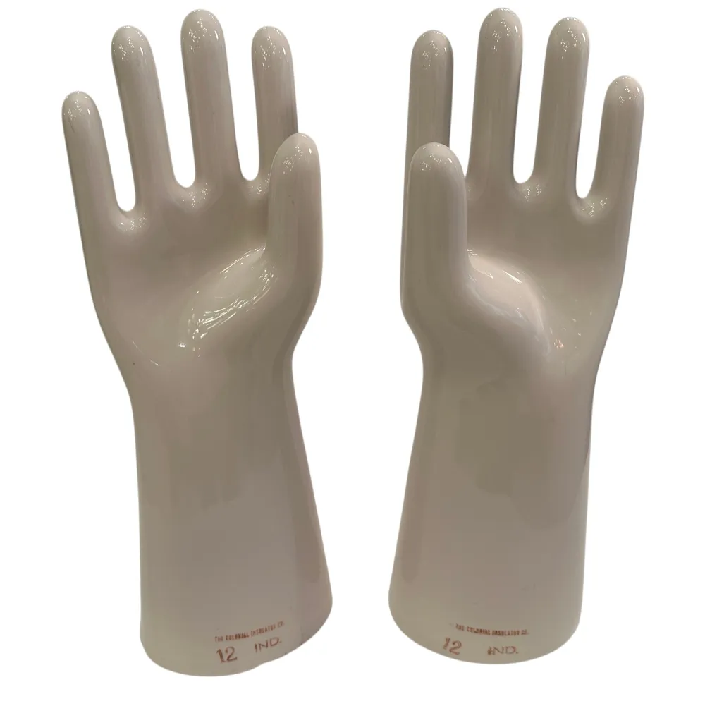 Coppia di mani in ceramica, antiche e lucide, con dettagli nella forma in uno sfondo neutro.