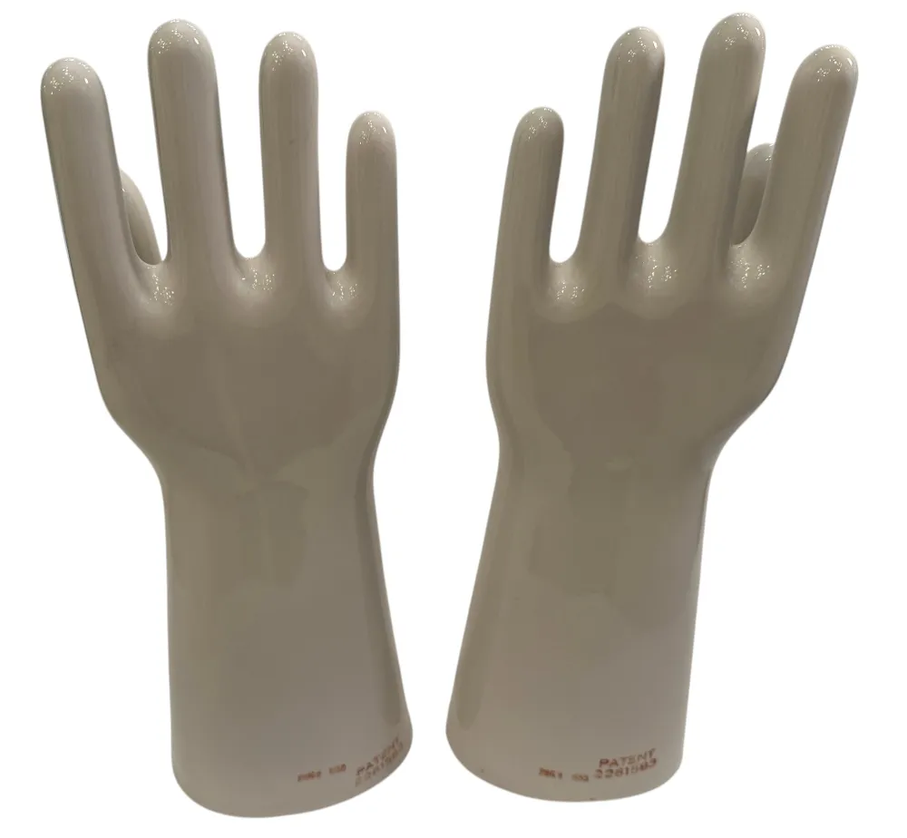 Coppia di mani in ceramica, antiche e lucide, con dettagli nella forma in uno sfondo neutro.