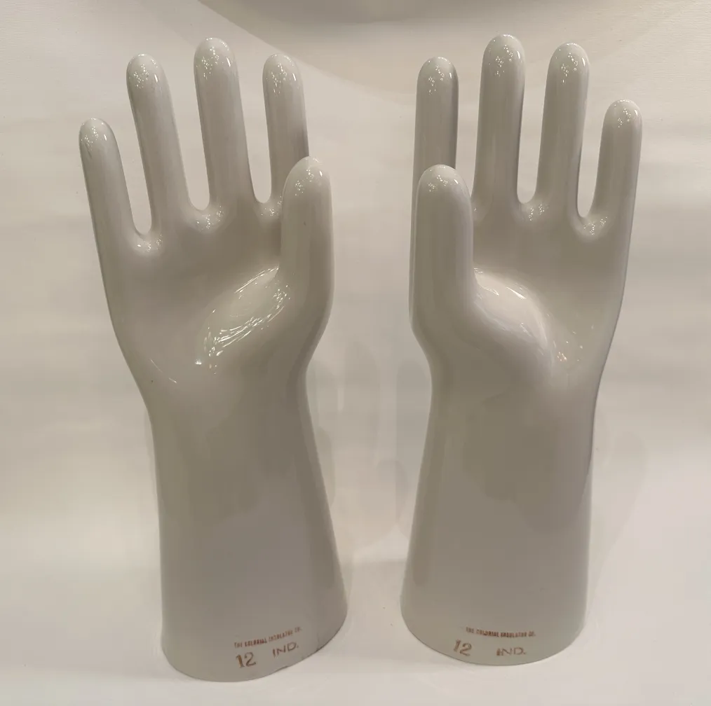 Coppia di mani in ceramica, antiche e lucide, con dettagli nella forma in uno sfondo neutro.