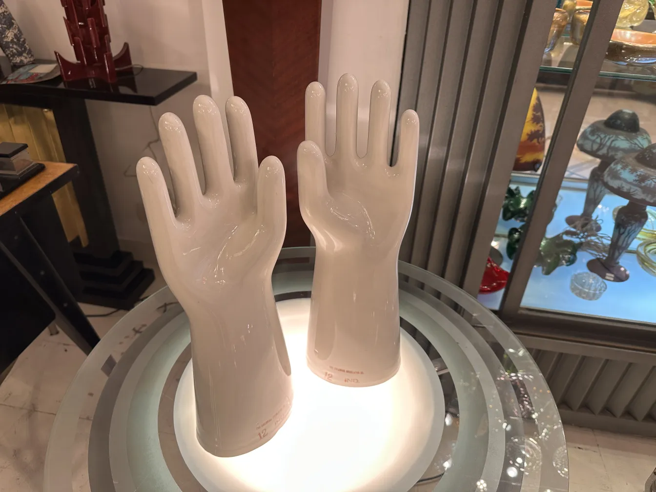 Coppia di mani in ceramica, antiche e lucide, con dettagli nella forma in uno sfondo neutro.
