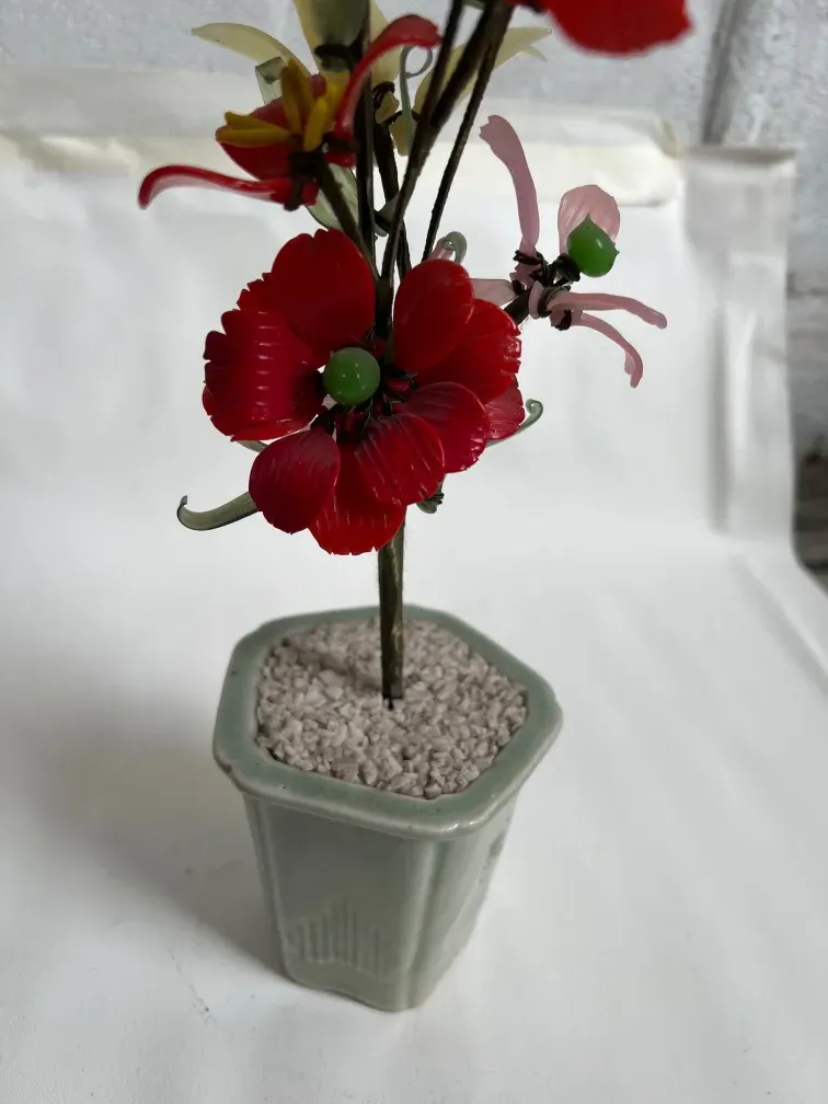 Bonsai ancien avec fleurs en plastique dans un pot décoratif.
