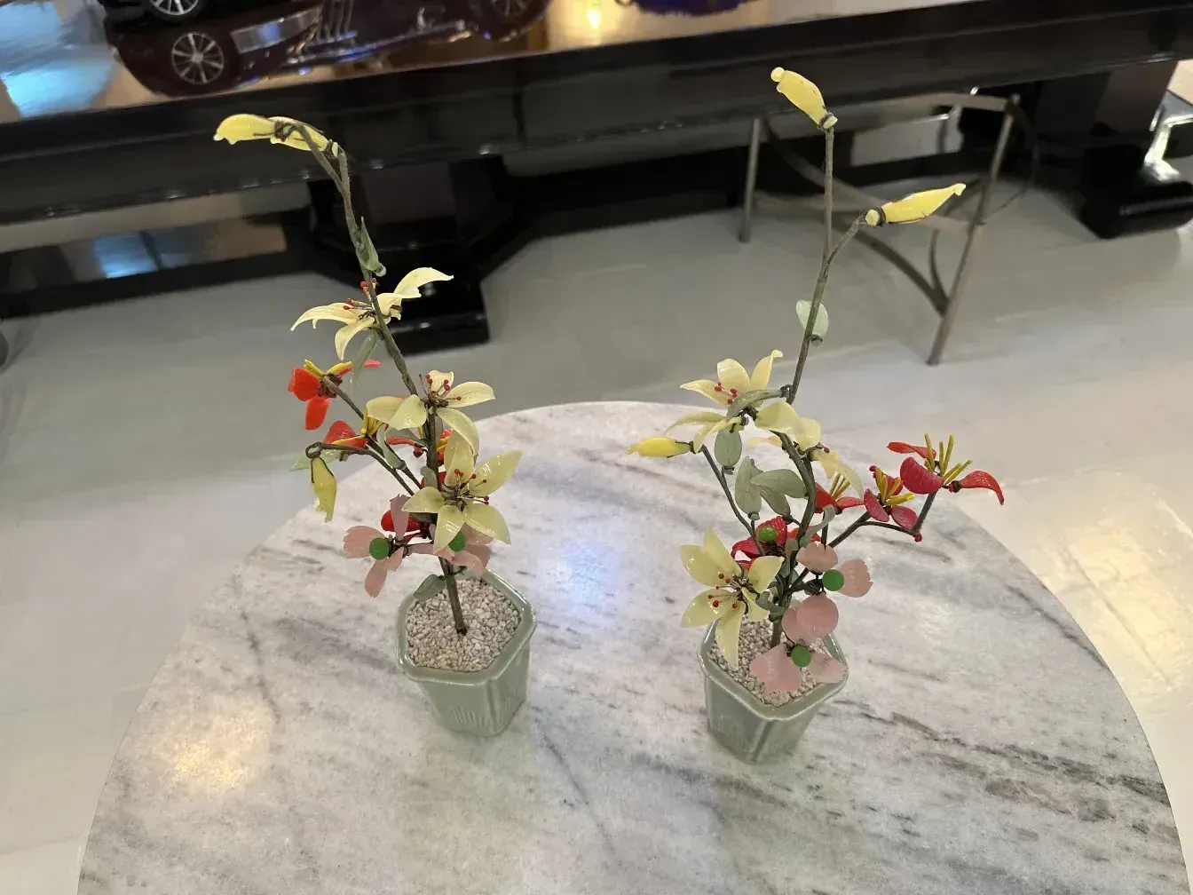 Antiguo bonsái con flores artificiales en una maceta decorativa.