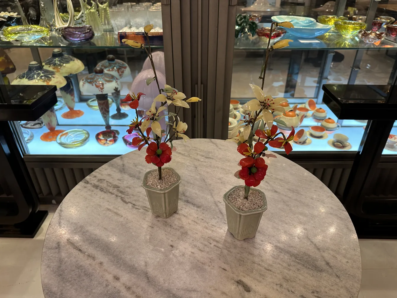 Bonsái antiguo con flores rojas y blancas en maceta decorativa, ambiente elegante.