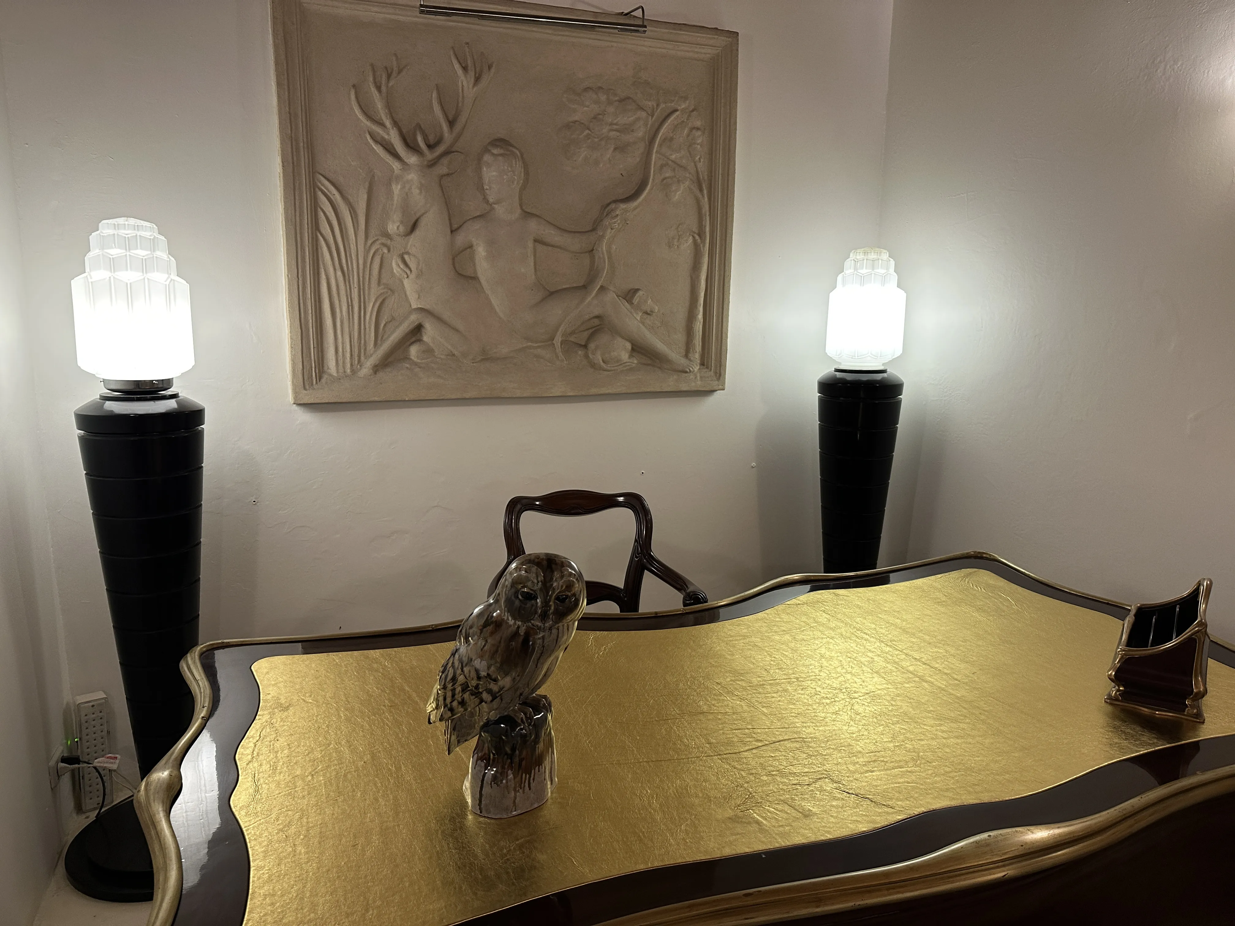 Eulenfigur auf einem goldenen Tisch mit alten Lampen.