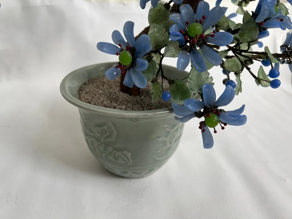 Antiker dekorativer Bonsai mit blauen Blumen in grünem Topf.
