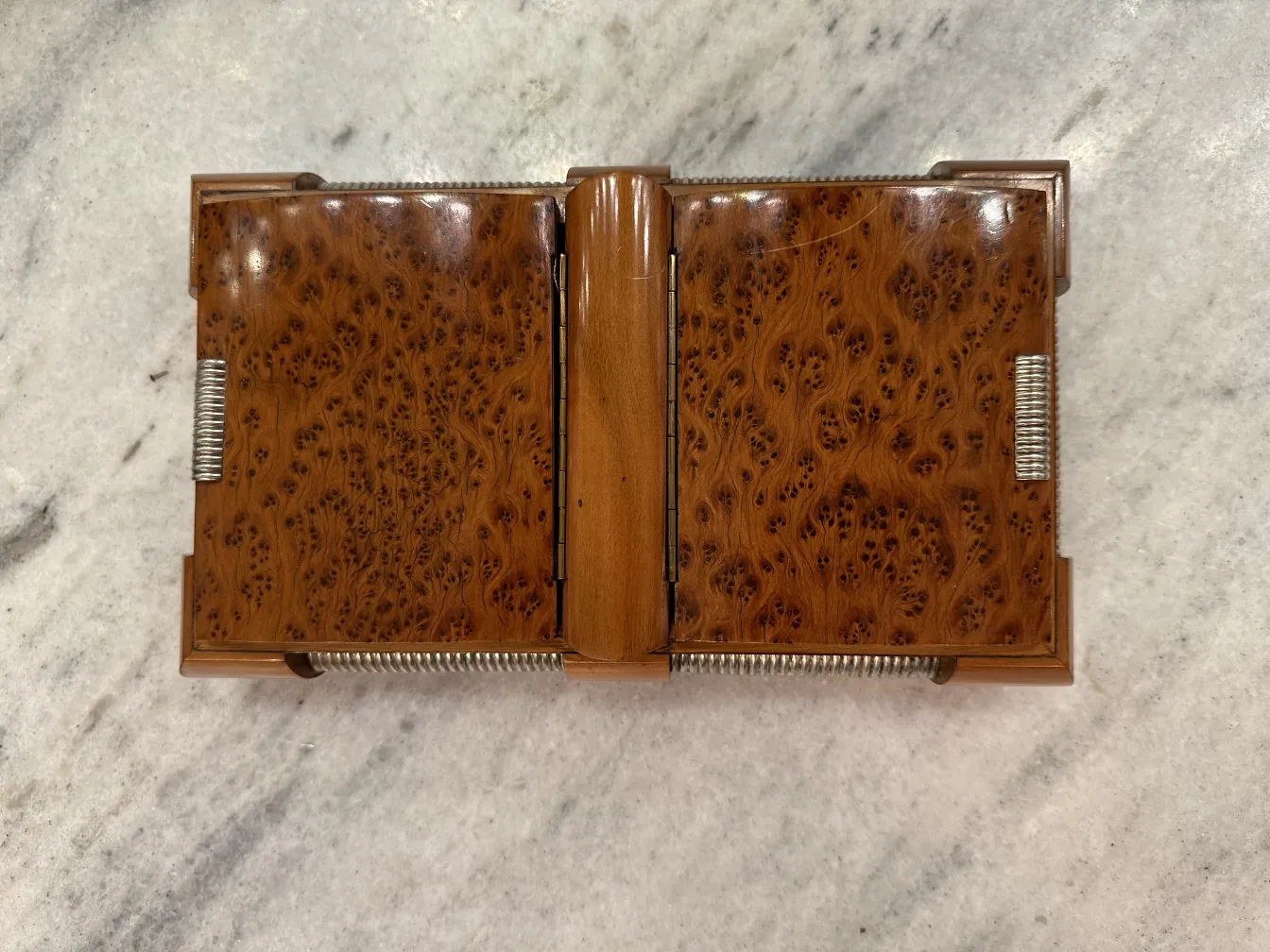 Scatola antica in legno con dettagli intricati, chiusa su una superficie chiara.