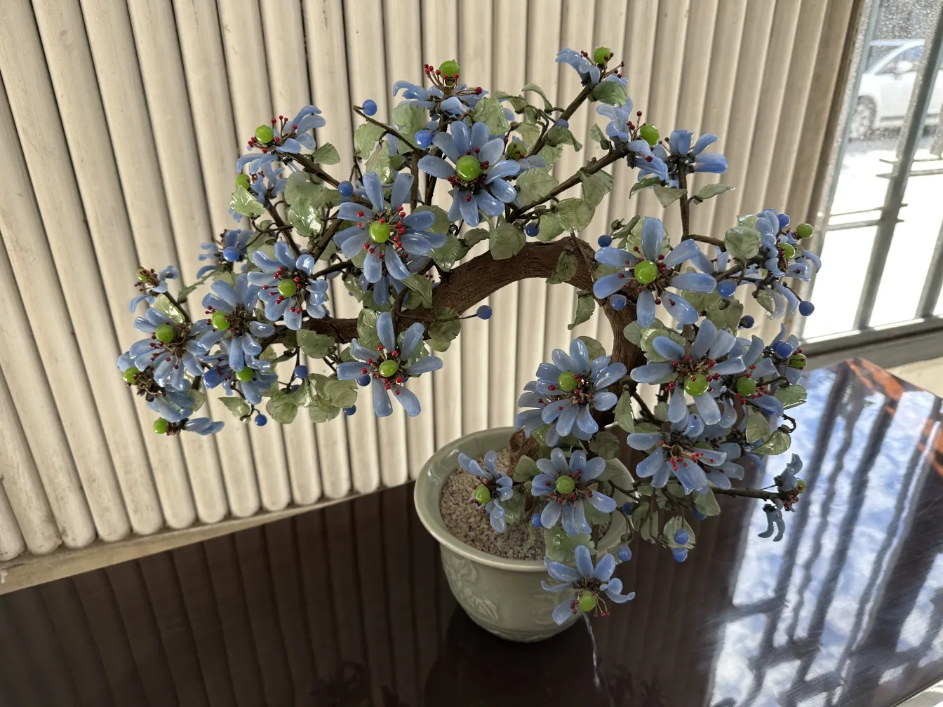 Antiker Bonsai mit dekorativen blauen und grünen Blumen.