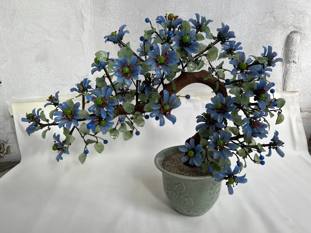 Bonsai antique avec des fleurs bleues et un feuillage vert clair.