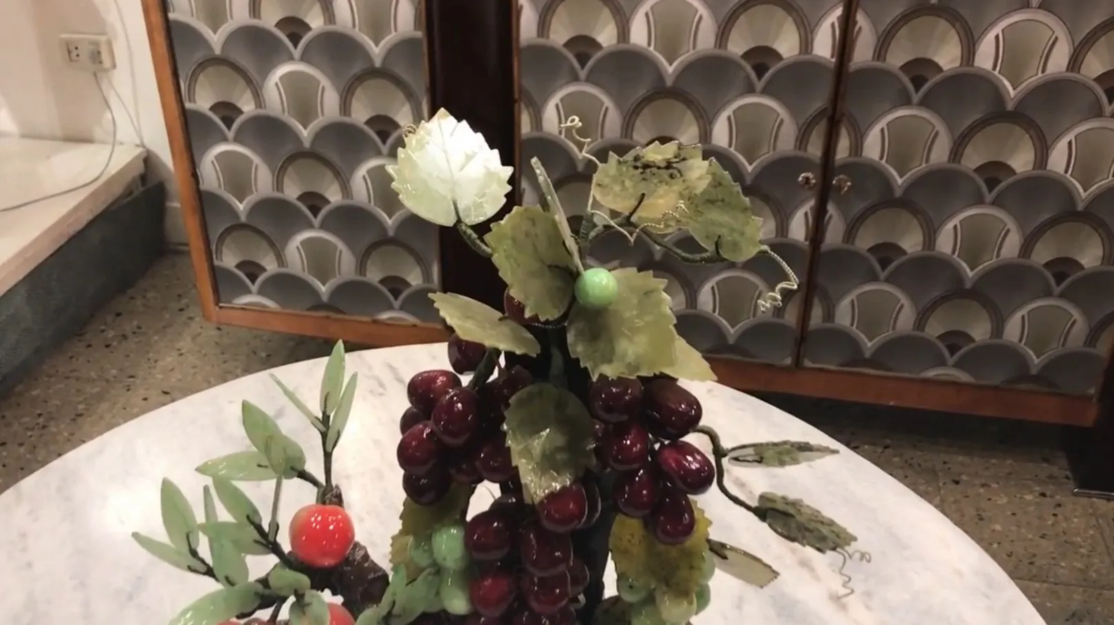 Bonsai antico con foglie verdi e ciliegie rosse su un tavolo.