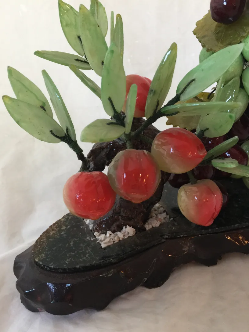 Bonsái antiguo con hojas verdes y frutas decorativas rojas