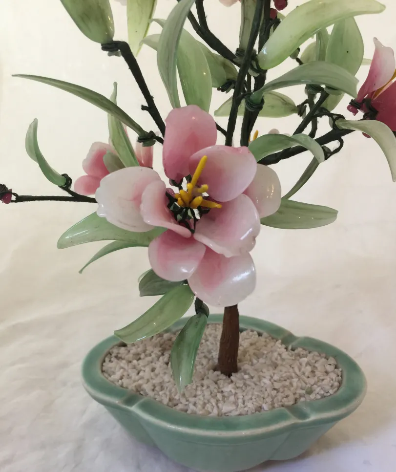 Antique bonsai with pink flowers and green leaves