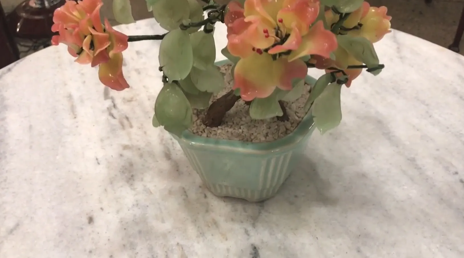 Bel bonsai antico con fiori in tonalità arancioni e verdi in una ciotola di ceramica.