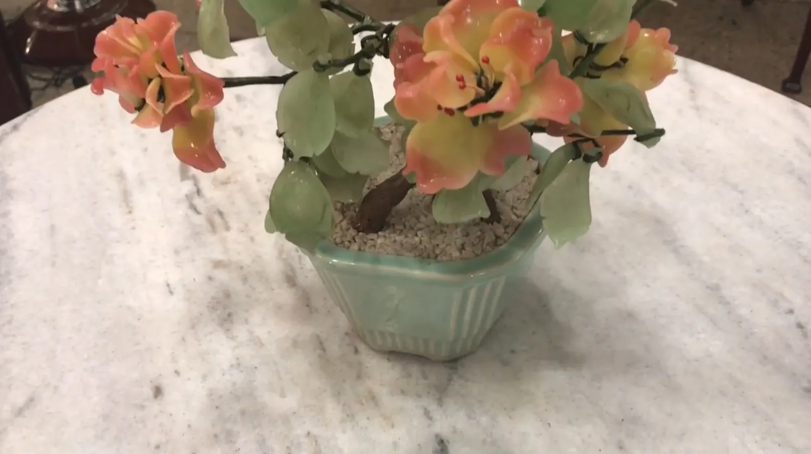 Bonsai antigo com flores coloridas em um vaso decorativo.