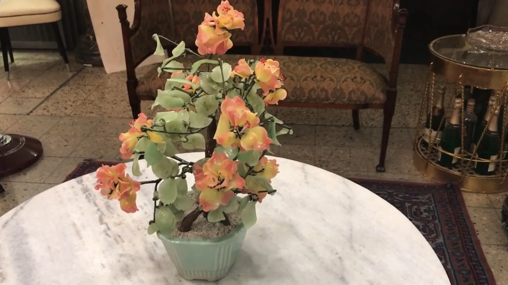 Bonsai antigo com flores coloridas em uma mesa elegante.