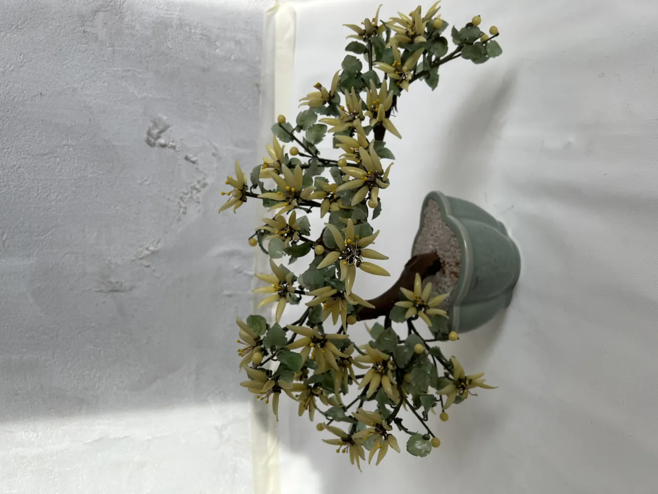 Bonsai antigo decorativo com flores amarelas em vaso verde.