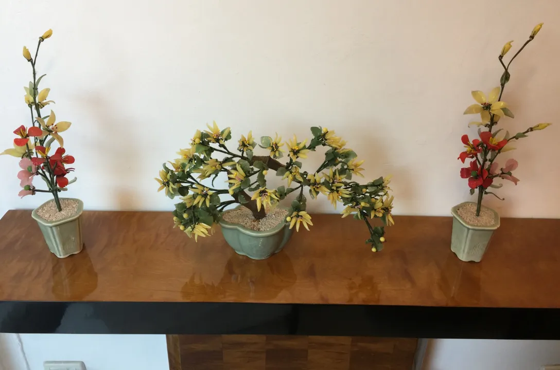 Tre bonsai antichi con fiori secchi su un tavolo di legno.