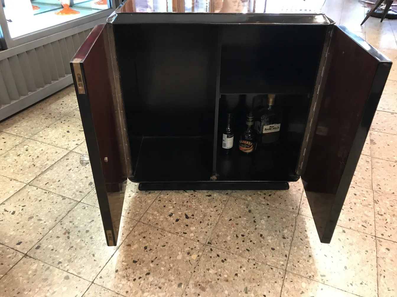 Antiker Cocktailschrank mit sichtbaren Flaschen innen.